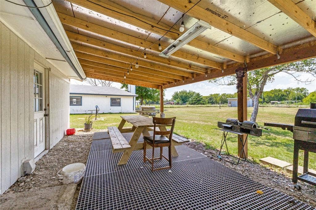 7400 County Road 131A, Terrell, TX 75161 Covered patio featuring an exposed timber-beam ceiling, reflective paneling, and a grid-style metal flooring surface