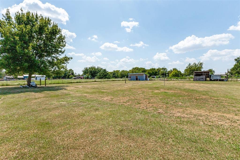 7400 County Road 131A, Terrell, TX 75161 Expansive level acreage featuring mature trees, wire perimeter fencing, and multiple outbuildings