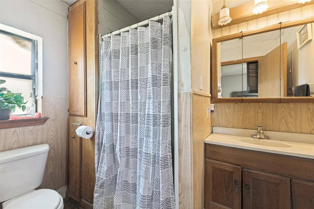 7400 County Road 131A, Terrell, TX 75161 Bathroom featuring wood-finish cabinetry, a built-in linen storage unit, a countertop-integrated basin, and a tri-panel mirrored medicine cabinet