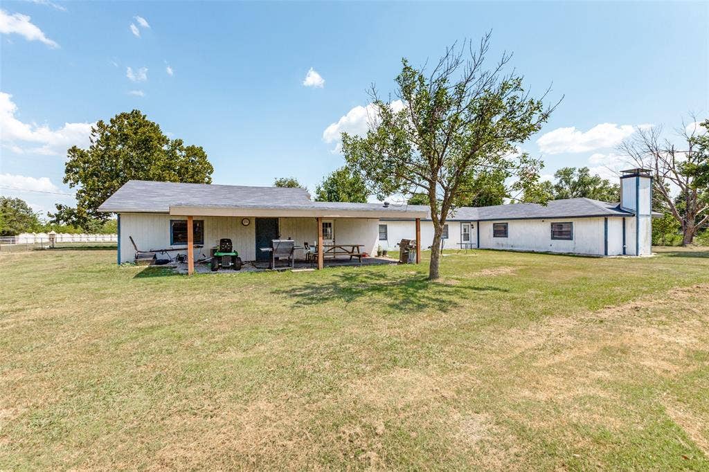 7400 County Road 131A, Terrell, TX 75161 Single-story ranch exterior featuring a covered patio, exterior chimney, vertical siding, and expansive grounds