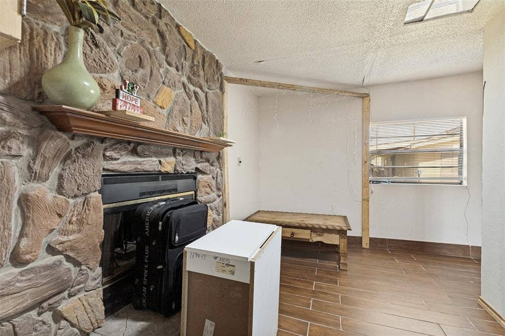 7400 County Road 131A, Terrell, TX 75161 Floor-to-ceiling natural stone fireplace with a wood mantel, wood-finish tile flooring, and window with horizontal blinds