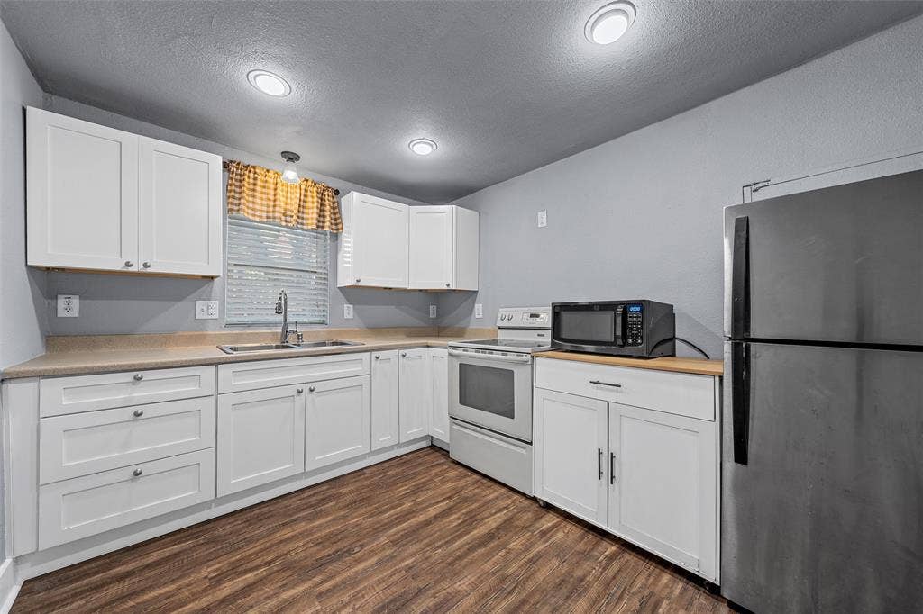 2222 Speight Avenue, Waco, TX 76706 Kitchen featuring white shaker-style cabinetry, wood-finish flooring, recessed lighting, and a stainless steel sink with a high-arch faucet