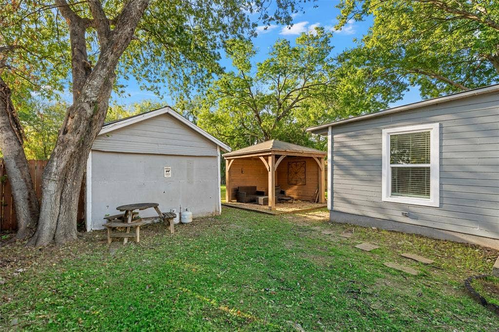 2222 Speight Avenue, Waco, TX 76706 Outdoor space featuring a wooden gazebo, detached storage structure, siding exterior, mature trees, and grass lawn