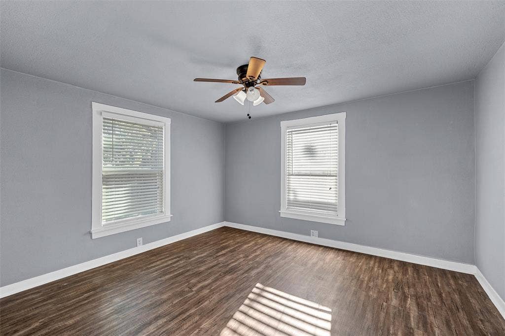2222 Speight Avenue, Waco, TX 76706 Room featuring wood-finish flooring, two windows with blinds, and a ceiling-mounted light fixture with fan