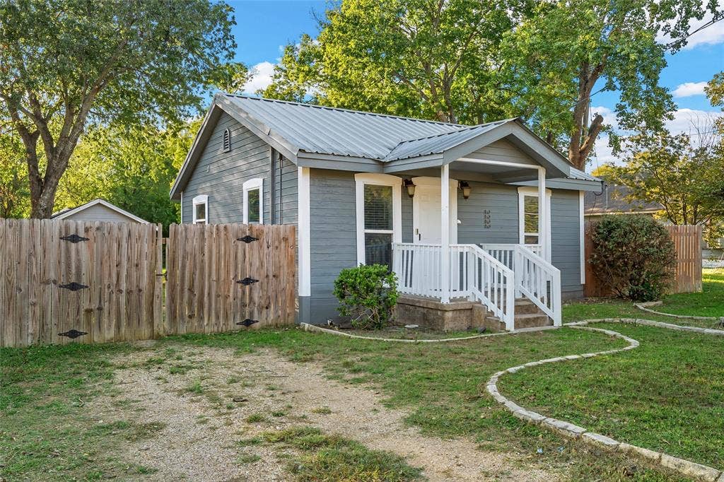 2222 Speight Avenue, Waco, TX 76706 Exterior featuring horizontal siding, a metal roof, a covered front porch with white railing, and a fenced-in yard