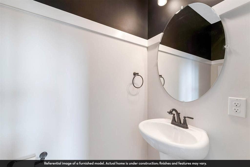3009 Merrick Drive, Crandall, TX 75114 Wall-mounted white pedestal sink with a dark metal two-handle faucet, oval wall mirror, and contrast wall trim with dark upper-wall detailing