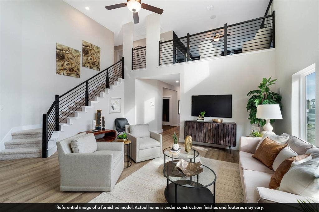 3009 Merrick Drive, Crandall, TX 75114 Two-story living area featuring vaulted ceilings, wood-finish flooring, a mezzanine overlook with black horizontal metal railings, and a staircase with matching metal railing