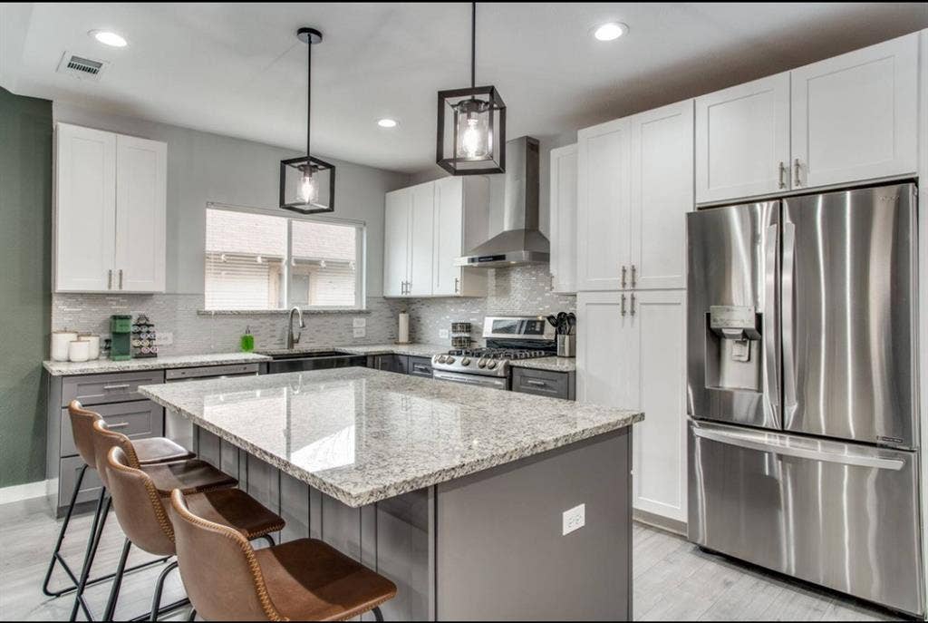 1606 W 12th Street, Dallas, TX 75208 Kitchen featuring a central island with stone-finish countertops, stainless steel appliances, white upper cabinetry, grey lower cabinetry, and glass-paneled pendant lighting