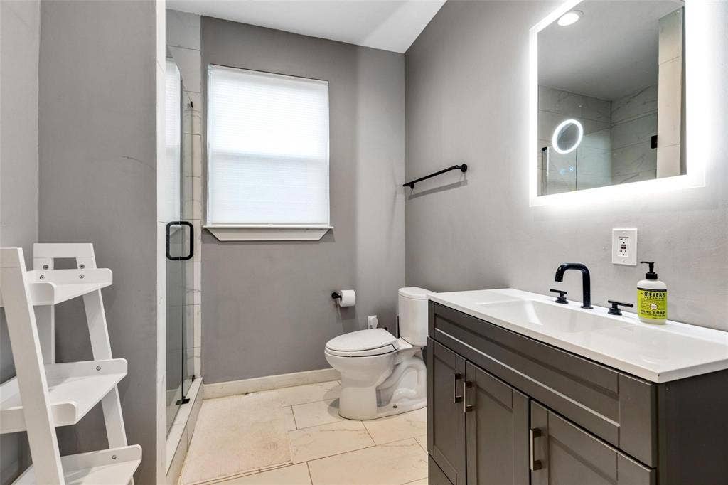 1606 W 12th Street, Dallas, TX 75208 Bathroom featuring a dark gray vanity with a white countertop, matte black fixtures, an integrated LED-backlit mirror, and tile flooring