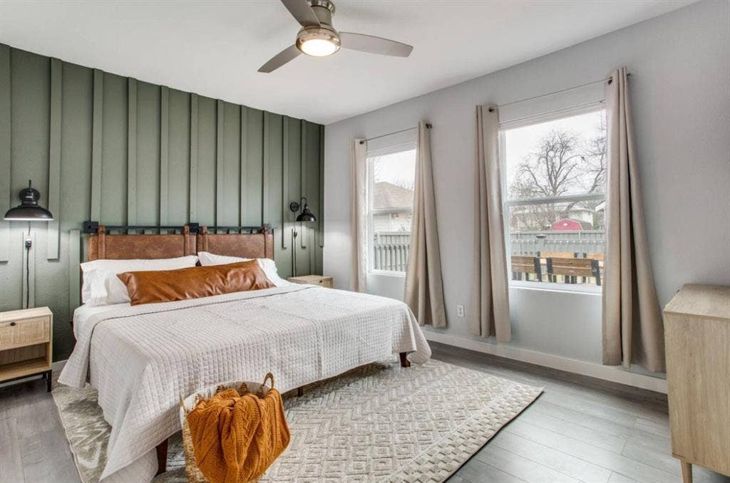 1606 W 12th Street, Dallas, TX 75208 Vertical board-and-batten accent wall, wood-finish flooring, ceiling fan with integrated lighting, and dual wall-mounted sconces
