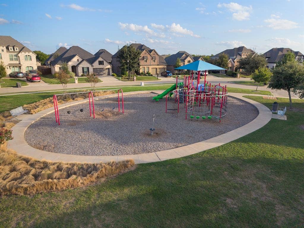 415 Rock Rose Lane, Wylie, TX 75098 Recreational area featuring a gravel playground with built-in play structures, swings, a shade canopy, and concrete perimeter curbing