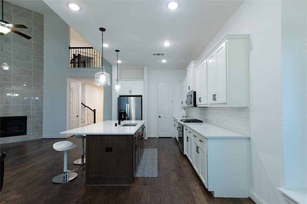 415 Rock Rose Lane, Wylie, TX 75098 Kitchen featuring white cabinetry, center island with stone-finish countertop, stainless steel appliances, and dark wood-finish flooring