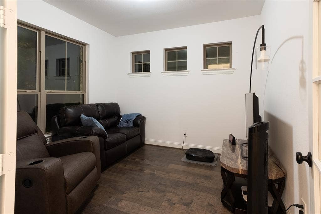 415 Rock Rose Lane, Wylie, TX 75098 Room featuring wood-finish flooring, three upper-wall square windows with muntin detailing, a large rectangular window, and a glass-paneled entry door