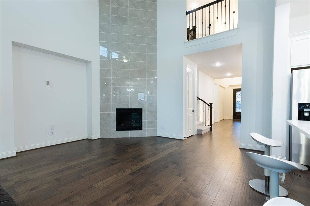 415 Rock Rose Lane, Wylie, TX 75098 Double-height ceiling, floor-to-ceiling tile fireplace surround, wood-finish flooring, and iron stair railing
