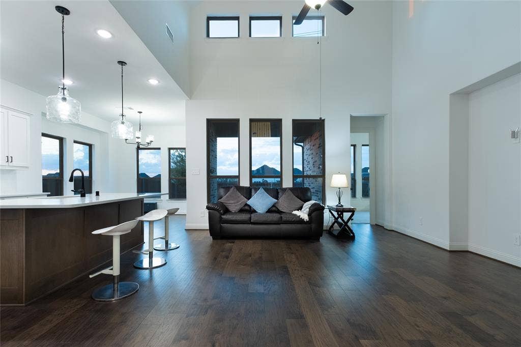415 Rock Rose Lane, Wylie, TX 75098 Open-concept space featuring double-height ceilings, wood-finish flooring, oversized windows, and a kitchen island with pendant lighting