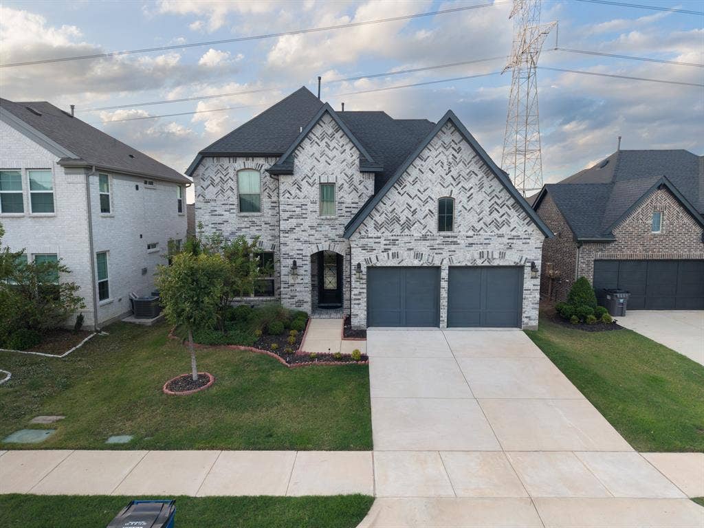415 Rock Rose Lane, Wylie, TX 75098 Two-story brick exterior with a multi-gabled roofline, an arched entryway, and an attached two-car garage