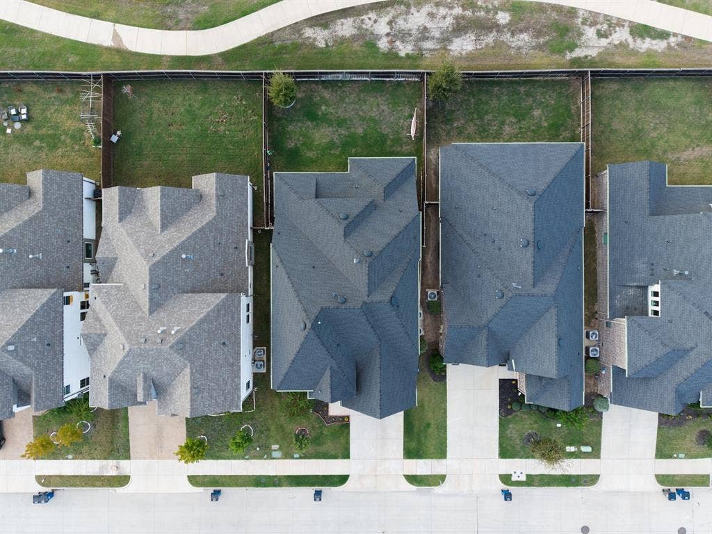 415 Rock Rose Lane, Wylie, TX 75098 Aerial perspective featuring a residential lot with a paved driveway, concrete walkway, private fenced backyard, and shingled roofline