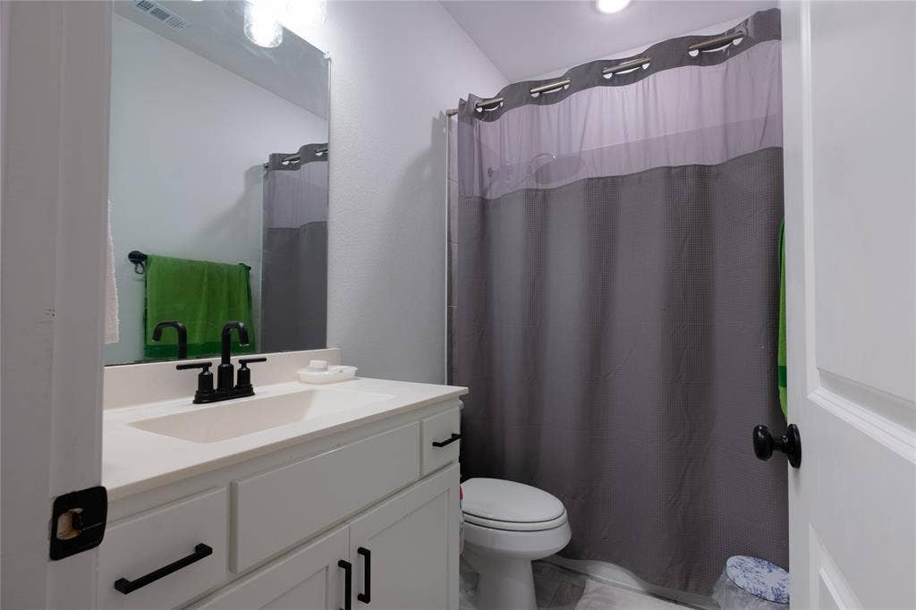 415 Rock Rose Lane, Wylie, TX 75098 Bathroom featuring a white vanity with matte black hardware, a rectangular sink, a large wall-mounted mirror, and a combination tub and shower