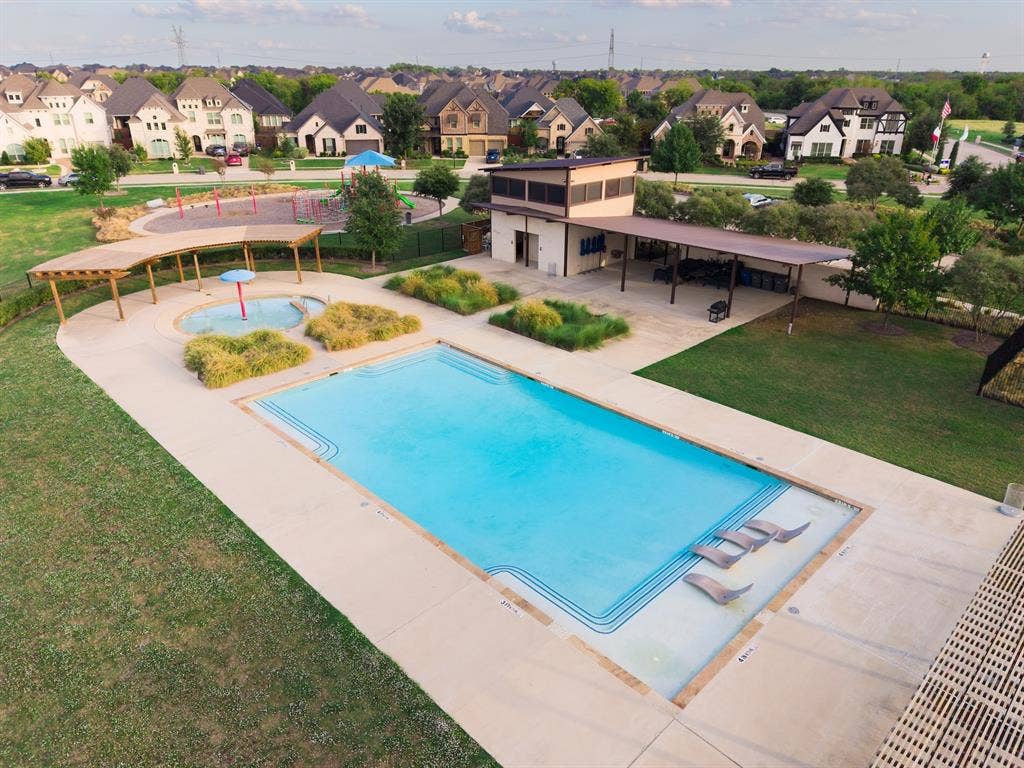 415 Rock Rose Lane, Wylie, TX 75098 Community amenities including a swimming pool with a tanning ledge, a children's splash pad, a shaded pergola, a clubhouse building, and a playground