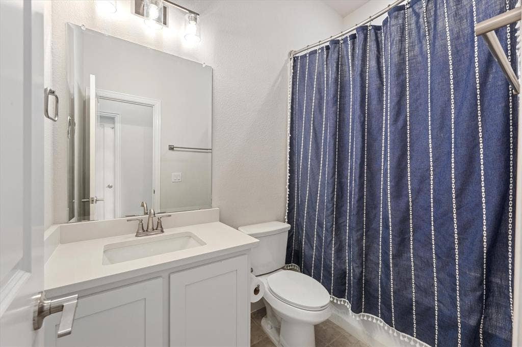 1958 Snowball Lane, Glenn Heights, TX 75154 Bathroom featuring a white vanity cabinet, solid-surface countertop with an integrated rectangular sink, wall-mounted mirror, three-light fixture, and a tub-shower combination with a brushed-metal finish faucet