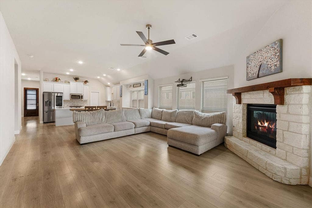 1958 Snowball Lane, Glenn Heights, TX 75154 Vaulted ceilings with recessed lighting, stone fireplace featuring a prominent wooden mantel, wood-finish flooring, and white cabinetry