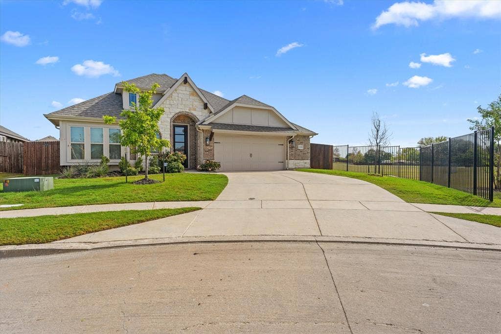 1958 Snowball Lane, Glenn Heights, TX 75154 Exterior facade featuring a combination of stone and siding, arched entryway, multi-gable roofline, attached multi-car garage, and metal perimeter fencing