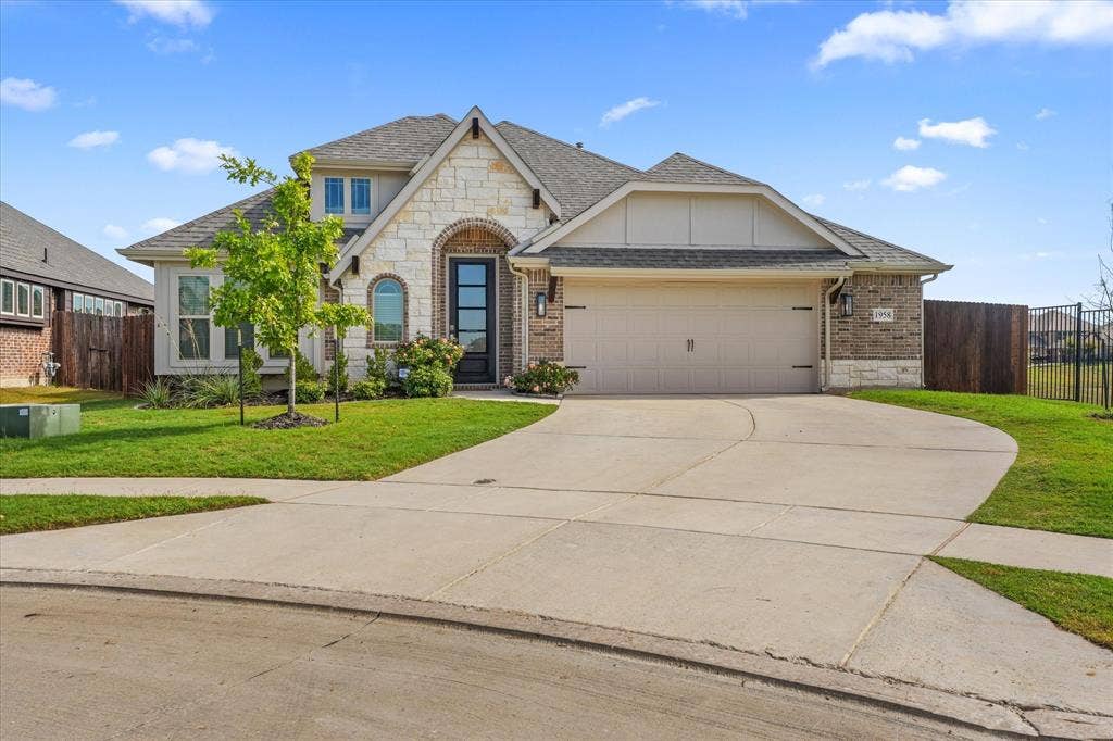 1958 Snowball Lane, Glenn Heights, TX 75154 Exterior facade featuring a combination of stone and brick masonry, arched entryway, multi-pane glass front door, and a two-car attached garage