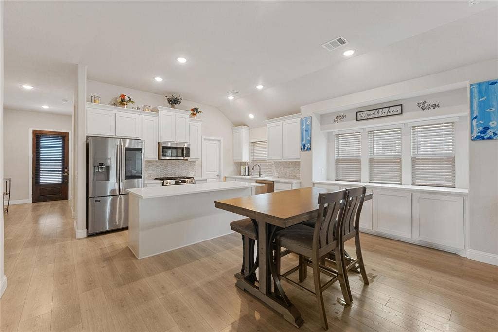 1958 Snowball Lane, Glenn Heights, TX 75154 Kitchen featuring white shaker-style cabinetry, quartz countertops, stainless steel appliances, wood-finish flooring, and built-in window seating with lower storage