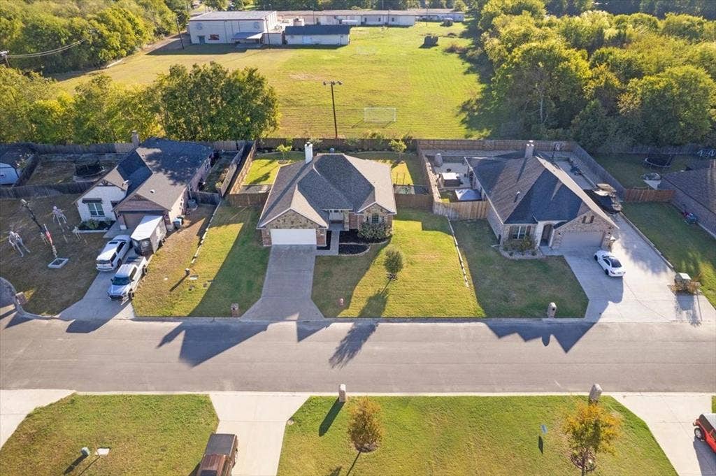 401 Mesa, Lone Oak, TX 75453 Aerial perspective featuring a multi-gabled roofline, brick and stone exterior, attached two-car garage, concrete driveway, and landscaped front lawn