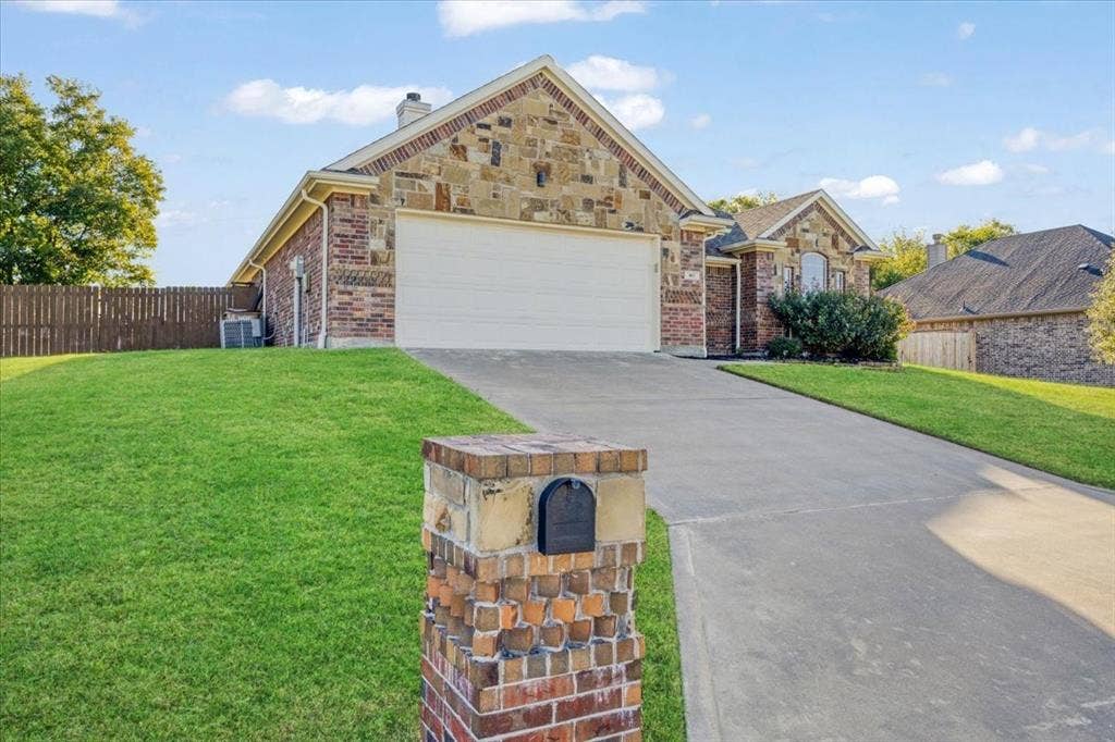 401 Mesa, Lone Oak, TX 75453 Single-story residence featuring a mixed stone and brick facade, attached two-car garage, concrete driveway, and a matching stone-clad mailbox post