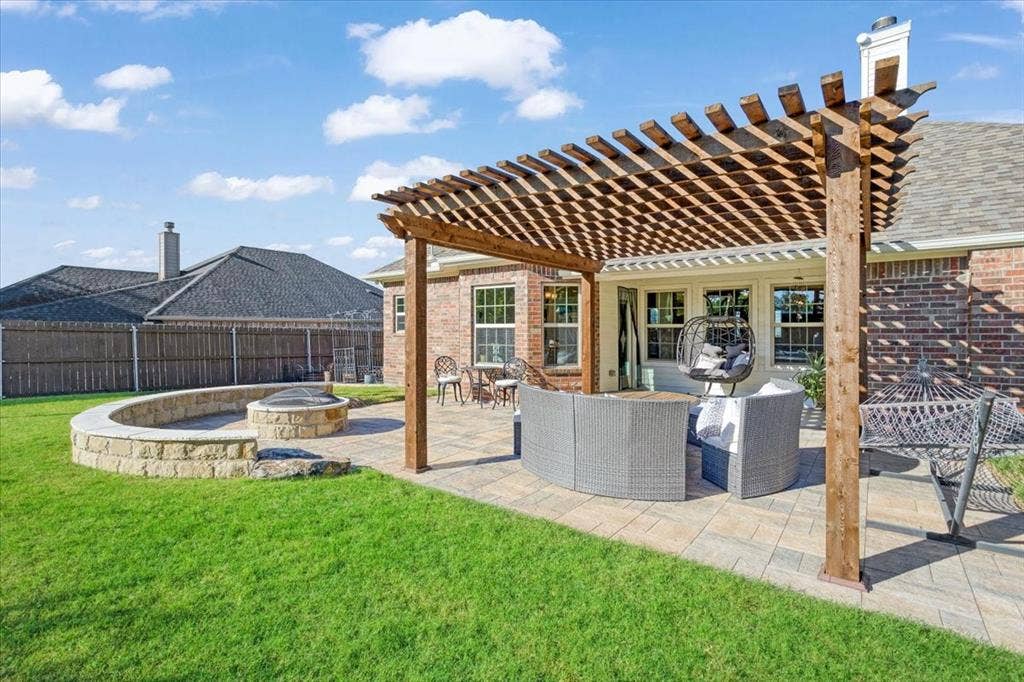 401 Mesa, Lone Oak, TX 75453 Backyard featuring a custom wood-beam pergola, stone-paver patio, and built-in stone fire pit with a curved retaining wall