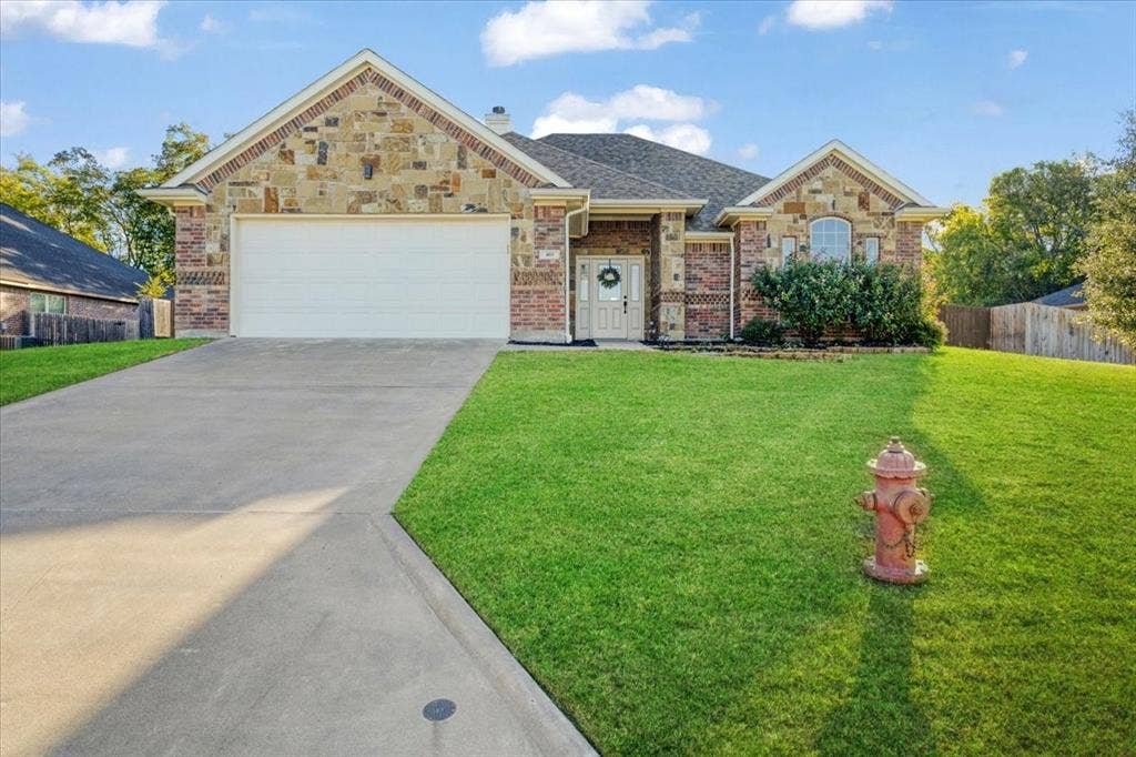 401 Mesa, Lone Oak, TX 75453 Single-story residence featuring a partial stone and brick veneer exterior, arched entryway, concrete driveway, and gabled roofline