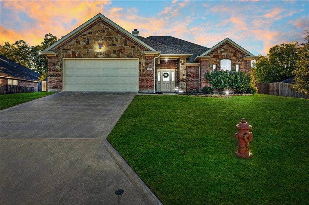 401 Mesa, Lone Oak, TX 75453 Single-story exterior featuring multi-toned stone and brick masonry, a covered entryway, an arched window, and an attached two-car garage
