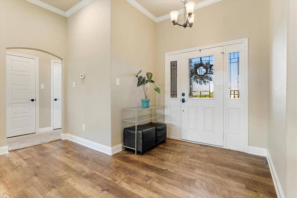 401 Mesa, Lone Oak, TX 75453 Entryway featuring wood-finish flooring, high ceilings with crown molding, an arched interior passageway, and a white front door with sidelights