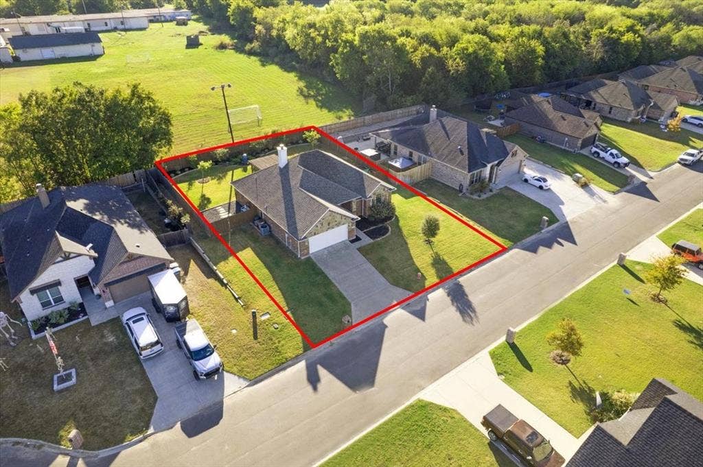 401 Mesa, Lone Oak, TX 75453 Aerial perspective of a single-story residence featuring a brick and stone exterior, a gabled roofline, an attached front-facing garage, and a fenced backyard