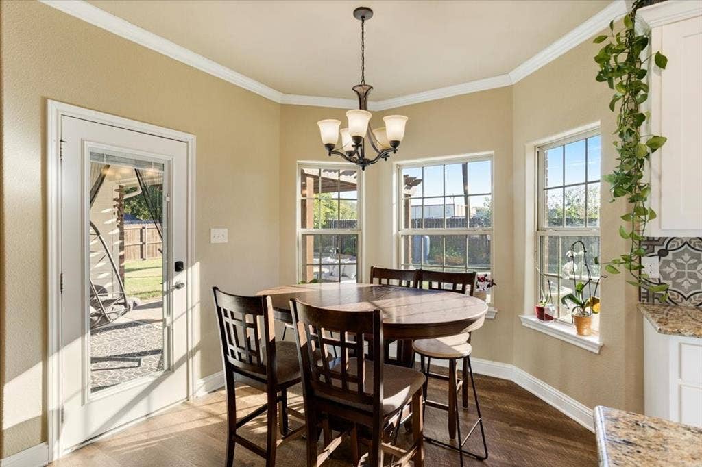 401 Mesa, Lone Oak, TX 75453 Bay window featuring three paneled windows, wood-finish flooring, white crown molding, a multi-light chandelier, and a glass-paneled exterior door