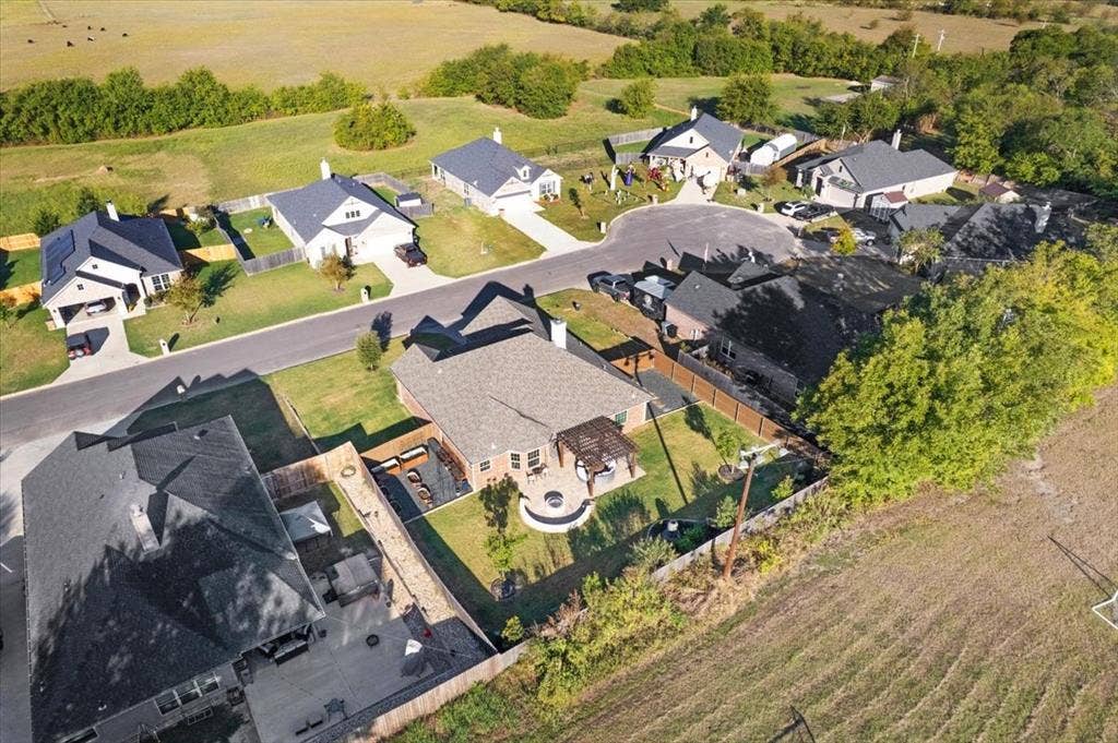 401 Mesa, Lone Oak, TX 75453 Aerial perspective featuring a single-story residence with a composite shingle roof, a backyard with a stone-surfaced fire pit, a wood-frame pergola, and a concrete patio