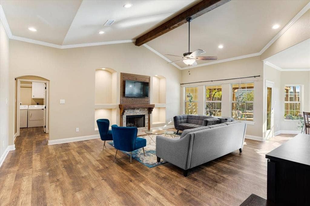 401 Mesa, Lone Oak, TX 75453 Vaulted ceilings featuring a stained wood beam, wood-finish flooring, stone-surround fireplace with a custom wood mantel, and built-in recessed shelving