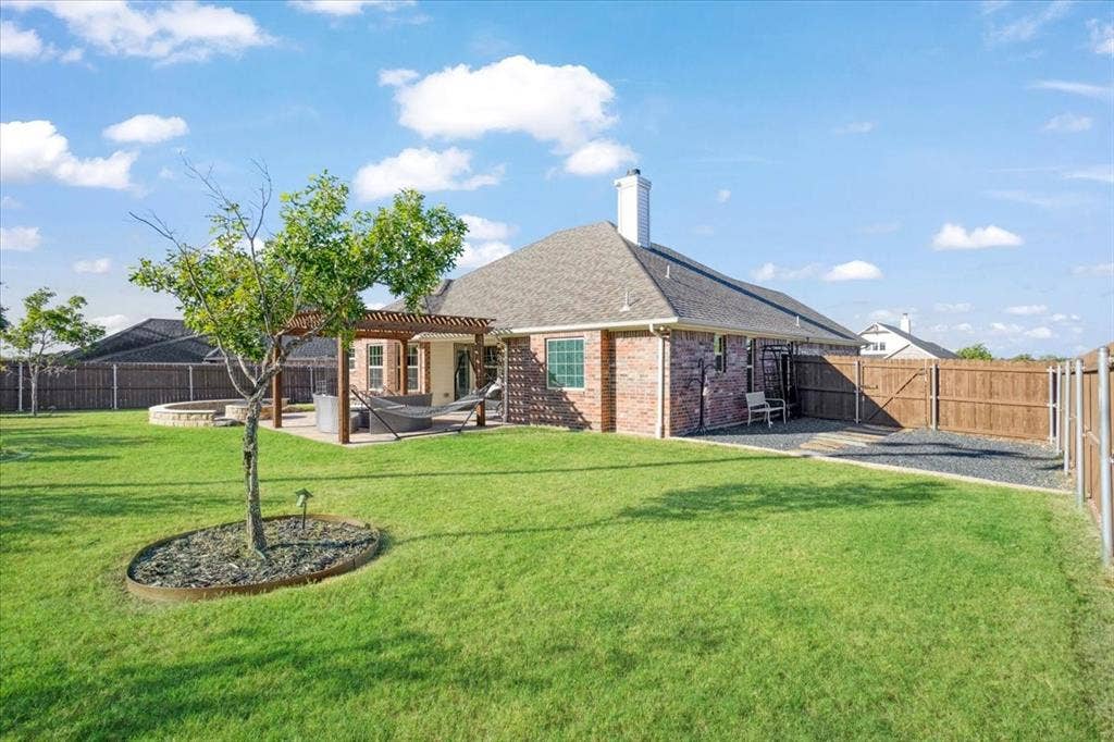 401 Mesa, Lone Oak, TX 75453 Expansive backyard featuring a brick exterior, covered wooden pergola, stone-lined fire pit, and full perimeter wood fencing