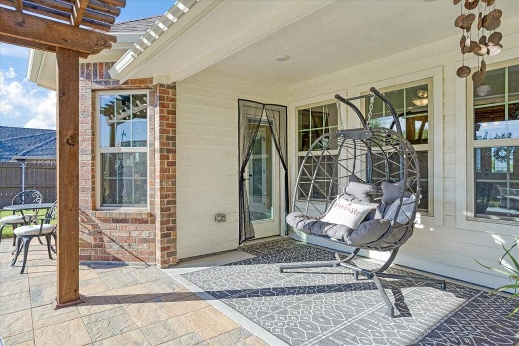 401 Mesa, Lone Oak, TX 75453 Covered rear patio featuring horizontal lap siding, brick masonry detailing, a timber pergola, and stone-finish tile flooring