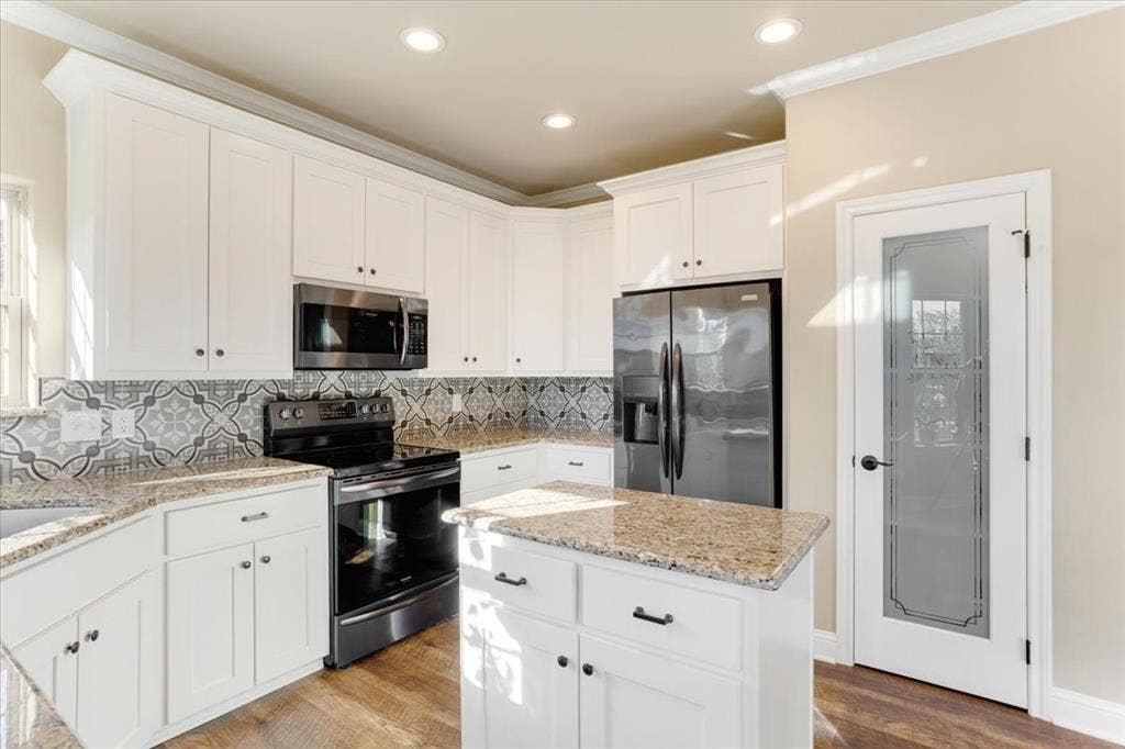 401 Mesa, Lone Oak, TX 75453 White cabinetry with stone countertops, patterned tile backsplash, stainless steel appliances, wood-finish flooring, and a glass-paneled interior door