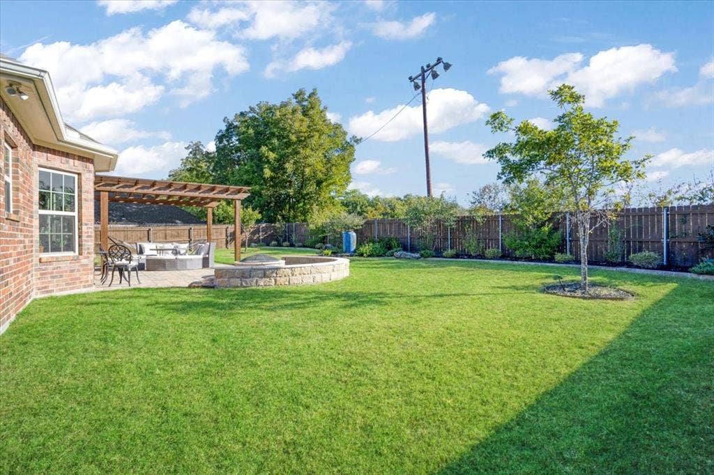 401 Mesa, Lone Oak, TX 75453 Backyard featuring a brick-exterior home, a wood pergola, a stone-surround fire pit, and a fenced perimeter