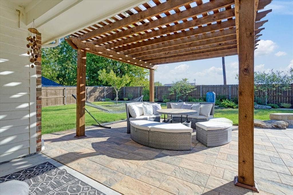 401 Mesa, Lone Oak, TX 75453 Covered patio featuring a timber-frame pergola, natural stone-finish pavers, a stone landscape border, and a fenced backyard