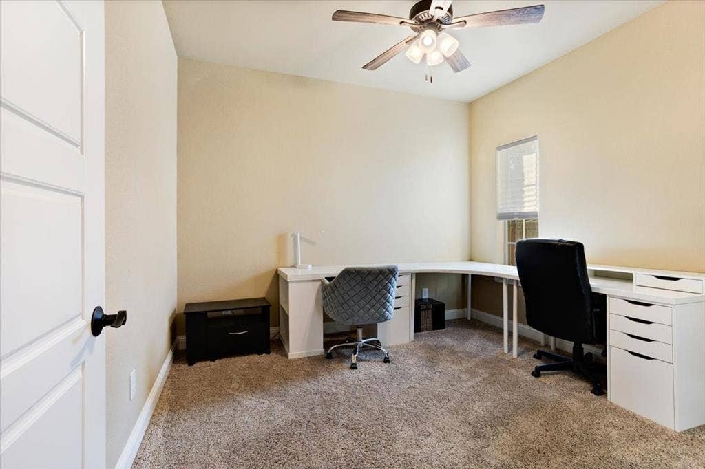 401 Mesa, Lone Oak, TX 75453 Neutral-toned interior room featuring wall-to-wall carpeting, a multi-blade ceiling fan with integrated lighting, a single-panel interior door with matte black hardware, and a window with fitted blinds