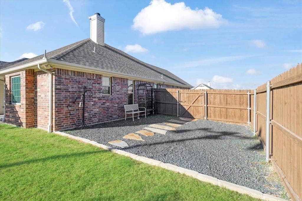401 Mesa, Lone Oak, TX 75453 Brick exterior with a chimney, stone paver pathway, gravel ground cover, and a wood privacy fence