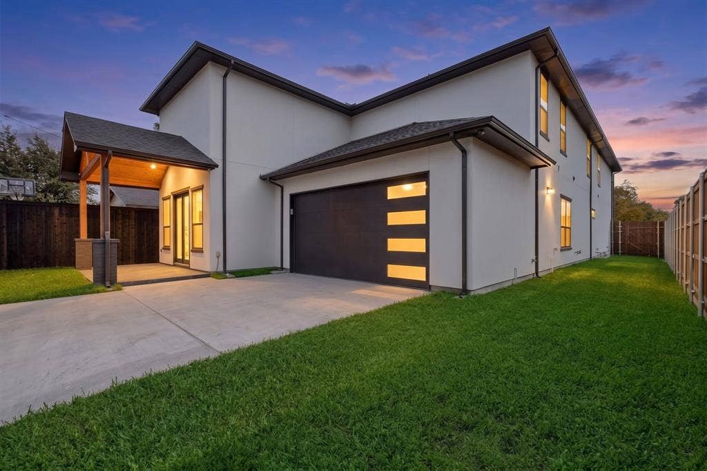 7503 Robin Road, Dallas, TX 75209 Modern two-story exterior featuring smooth stucco siding, a covered patio with wood-finish ceiling, and a multi-panel garage door with horizontal light inserts