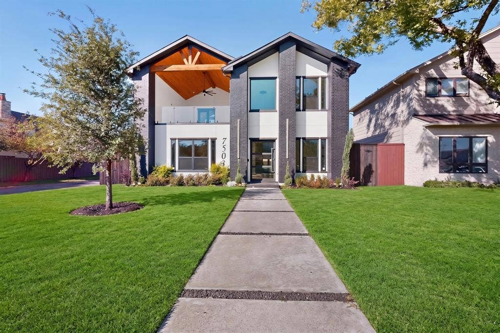 7503 Robin Road, Dallas, TX 75209 Two-story contemporary exterior featuring dark brick accents, high-contrast white siding, a covered upper-level balcony with wood-toned ceiling finishes, and a linear paver walkway