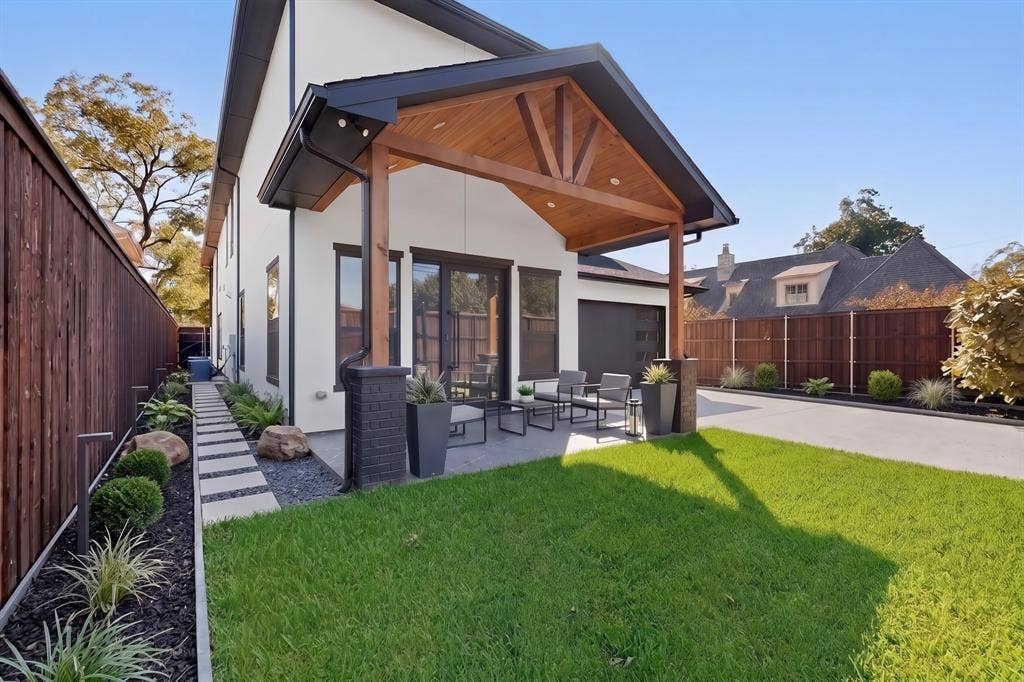 7503 Robin Road, Dallas, TX 75209 Covered patio featuring a wood-plank ceiling and recessed lighting, grounded by a concrete base and flanked by dark masonry pillars, complemented by a landscaped perimeter of stone pavers and lawn