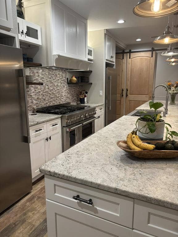 1794 County Road 4309 N, Greenville, TX 75401 Kitchen featuring white shaker-style cabinetry, stone countertops, stainless steel professional-grade range, mosaic tile backsplash, and wood-finish flooring
