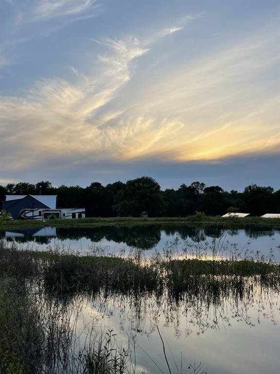 1794 County Road 4309 N, Greenville, TX 75401 Property featuring a private pond, expansive grounds, mature trees, and a distant metal-sided structure